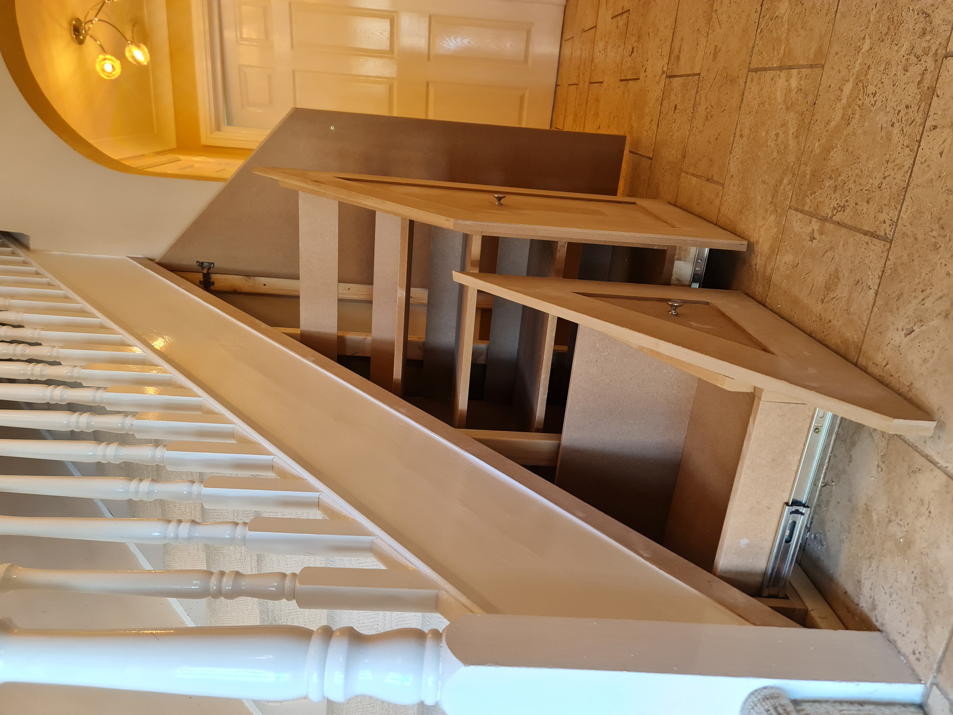 Crisp white bespoke under stairs pull-out shoe drawers and coat hooks