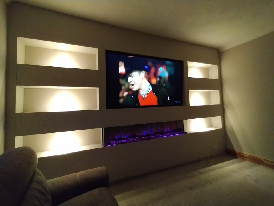 Built in media wall with a wide electric fireplace and floating shelves