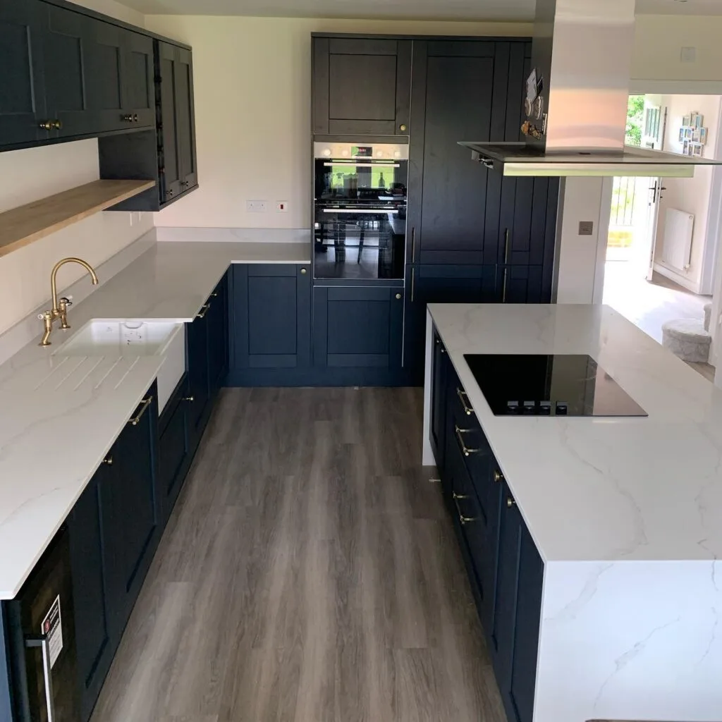 Navy shaker kitchen with a quartz island, brass tap and Belfast sink