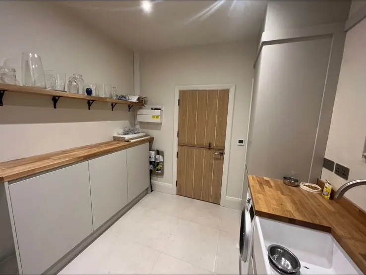 Utility room run of grey units with an oak worktop and open shelving